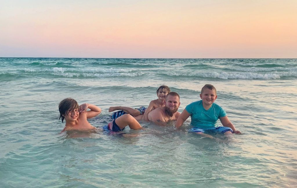 Guest photo showing family sitting in the ocean enjoying the waves