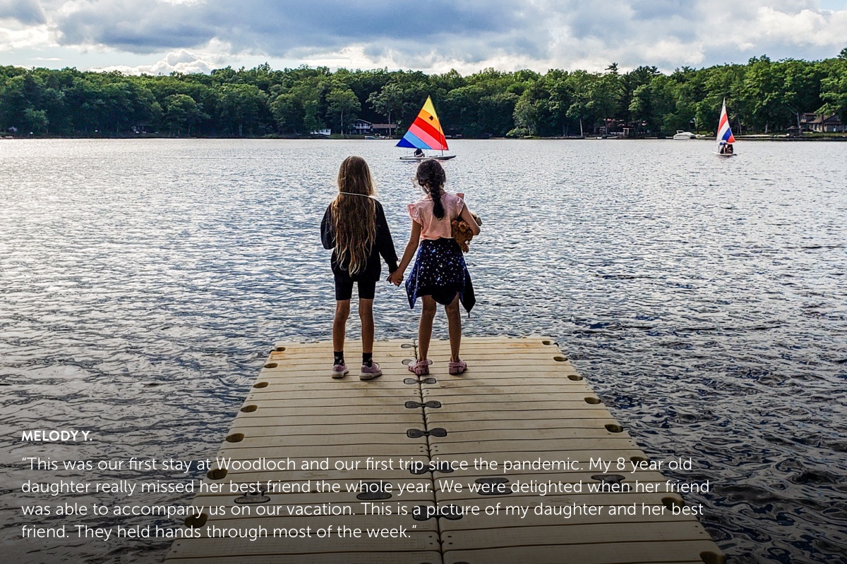 Photo submission from Melody Y., showing 2 girls holding hands standing on a pier looking out at sailboats out on the lake