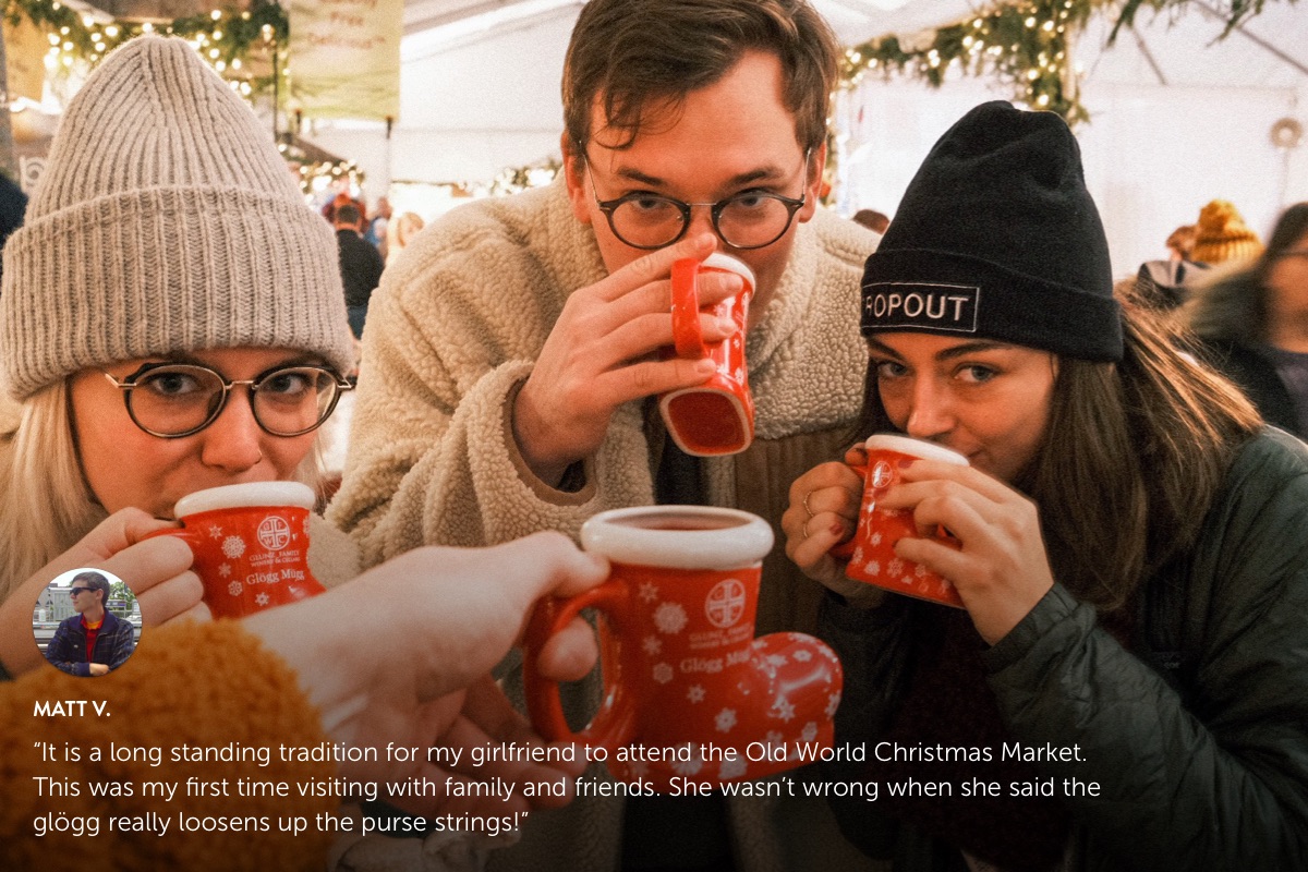 Photo submission from Matt V., showing 2 women and a man drinking warm beverages out of Christmas stocking cups at an outdoor Christmas market.