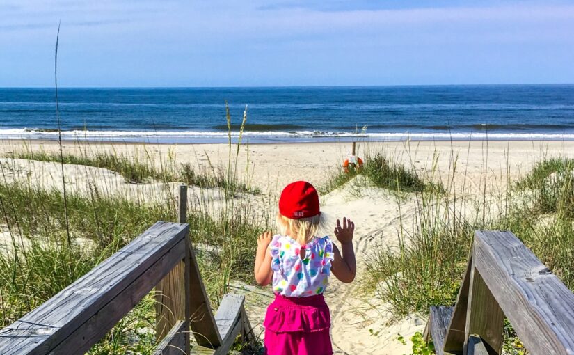Landscape orientation photo of a child on stairs overlooking sand dunes and the ocean